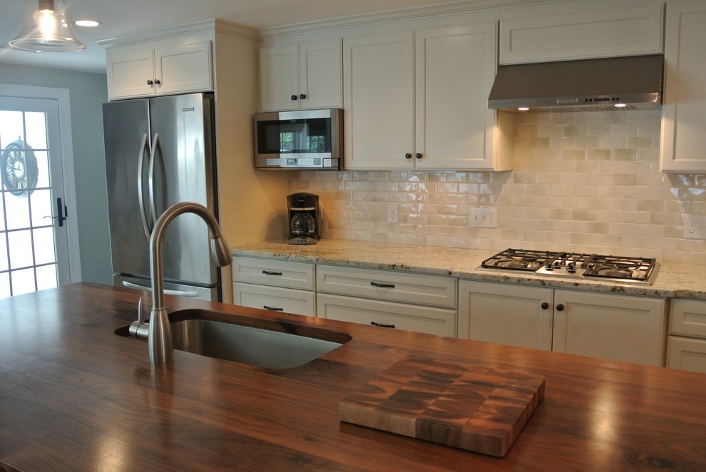 Transitional galley light wood floor eat-in kitchen photo in Boston with an undermount sink, shaker cabinets, white cabinets, wood countertops, white backsplash, ceramic backsplash, stainless steel appliances, an island and brown countertops