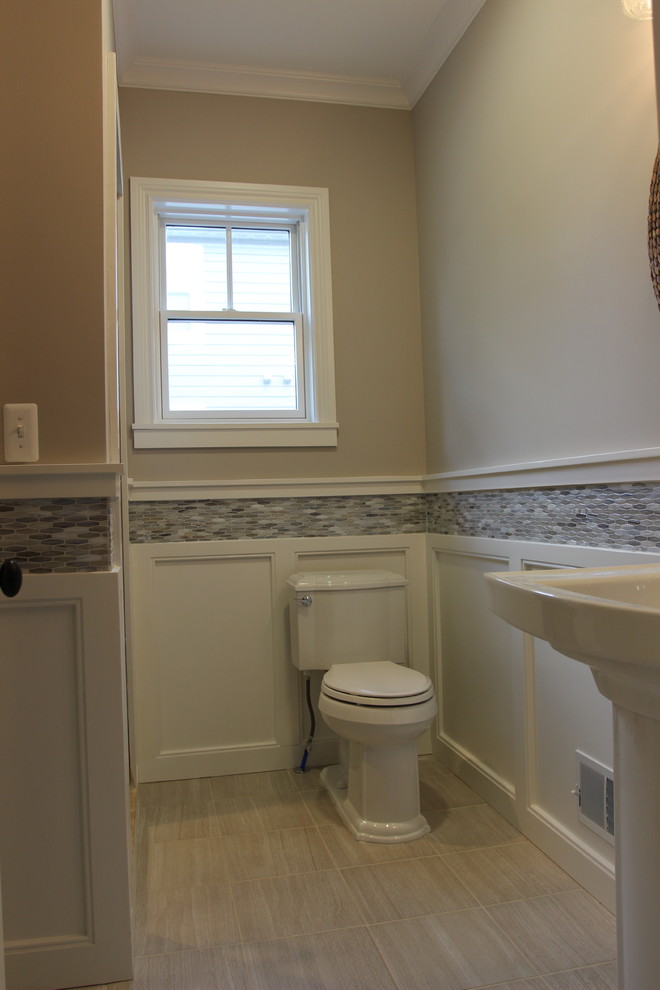 Mid-sized arts and crafts powder room in Detroit with a two-piece toilet, gray tile, glass tile, a pedestal sink, beige floor, beige walls and porcelain floors.