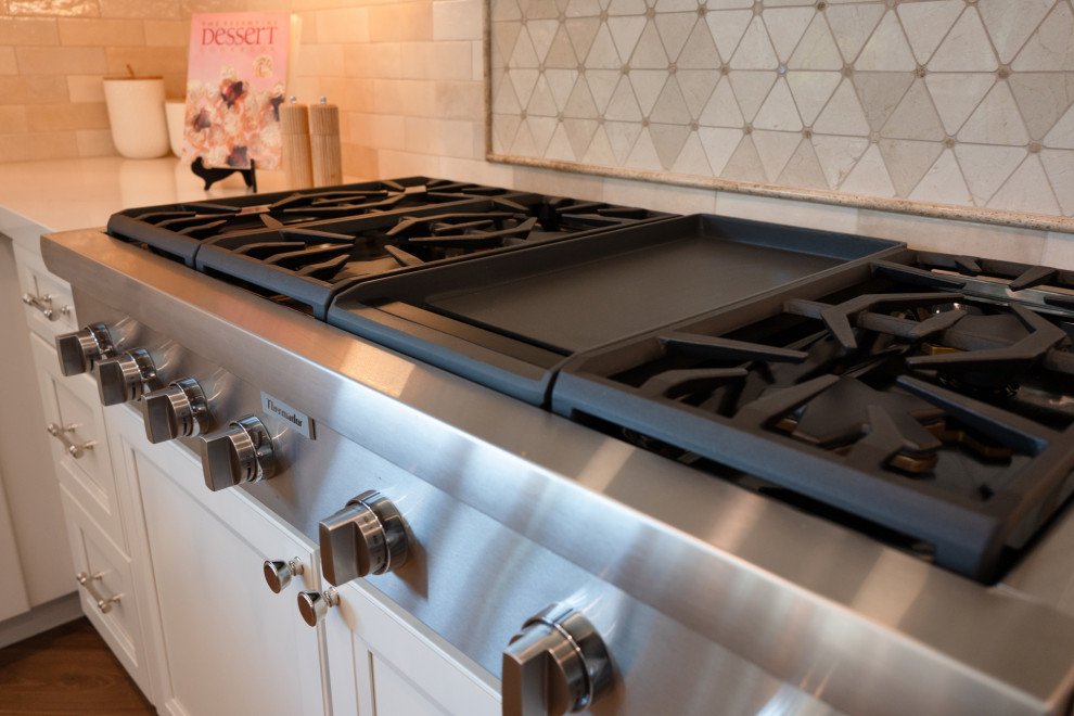 Example of a large transitional l-shaped vinyl floor and brown floor open concept kitchen design in San Diego with an undermount sink, shaker cabinets, white cabinets, quartz countertops, beige backsplash, porcelain backsplash, stainless steel appliances, an island and white countertops