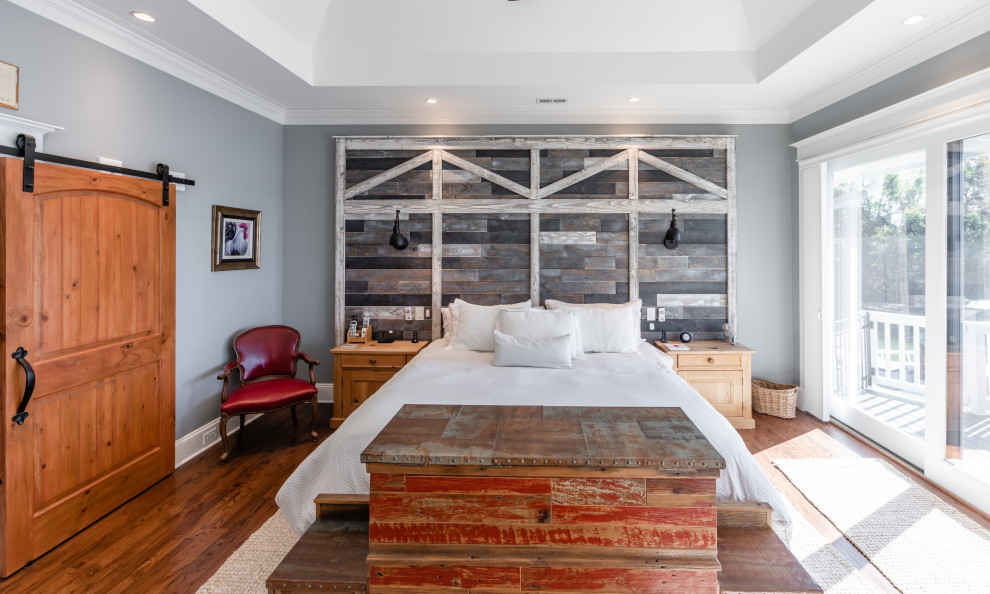 Modelo de dormitorio principal y abovedado de estilo de casa de campo grande con paredes azules, suelo de madera en tonos medios, suelo marrón y madera