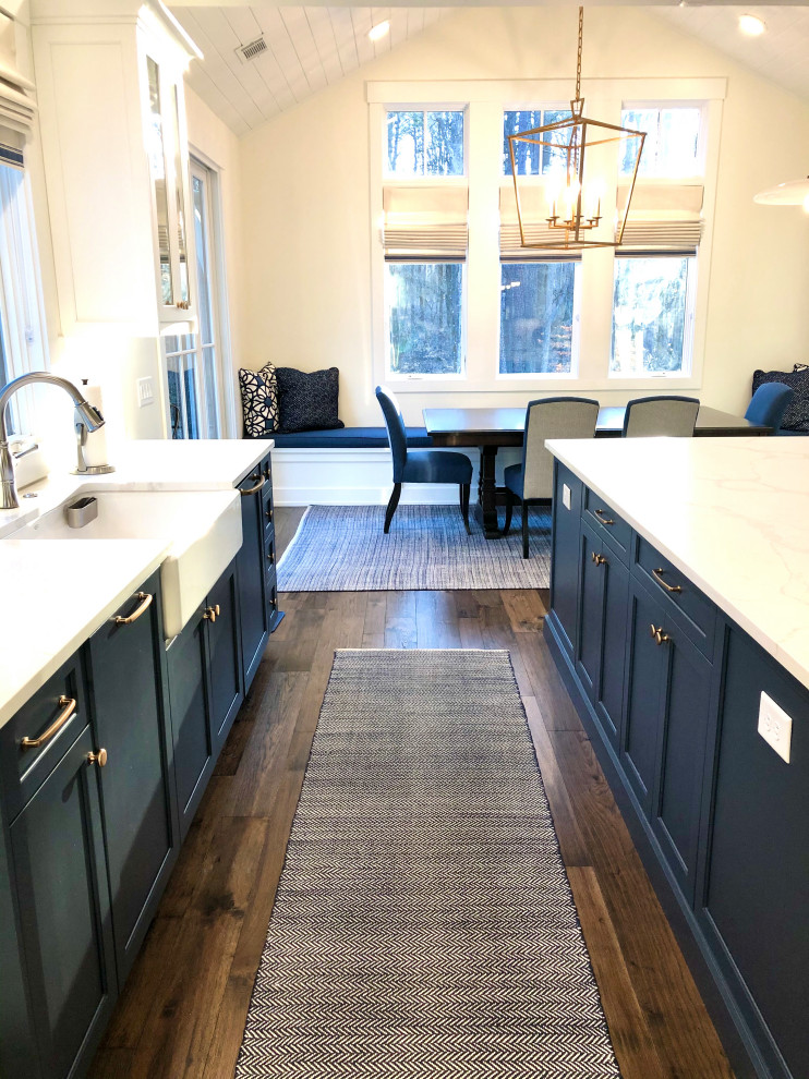 Photo of a mid-sized transitional l-shaped eat-in kitchen in Atlanta with a farmhouse sink, flat-panel cabinets, blue cabinets, marble benchtops, white splashback, window splashback, panelled appliances, dark hardwood floors, with island, brown floor, white benchtop and vaulted.