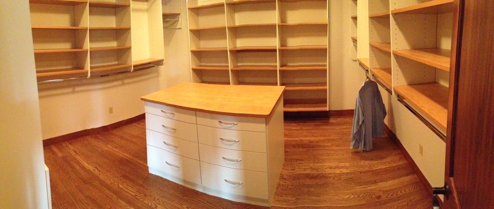 This is an example of a mid-sized modern gender-neutral walk-in wardrobe in Other with flat-panel cabinets, light wood cabinets and carpet.
