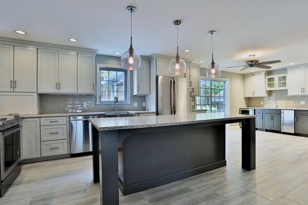 Large transitional l-shaped open plan kitchen in Boston with shaker cabinets, white cabinets, granite benchtops, with island, a farmhouse sink, grey splashback, subway tile splashback, stainless steel appliances, porcelain floors and beige floor.