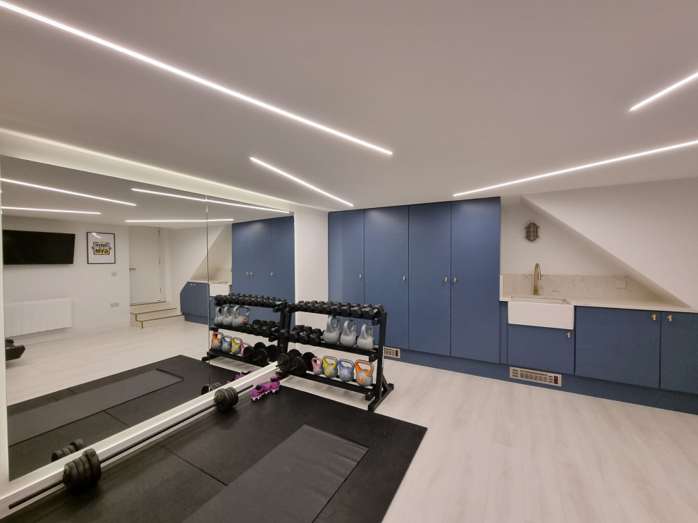 Mid-sized contemporary multipurpose gym in London with white walls, laminate floors, multi-coloured floor and recessed.
