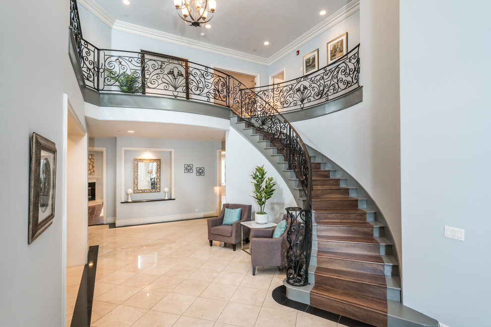 Expansive transitional wood curved staircase in Los Angeles with wood risers and metal railing.