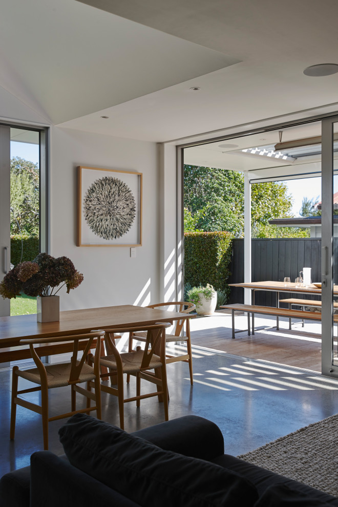 Mid-sized contemporary kitchen/dining combo in Auckland with white walls, concrete floors and grey floor.