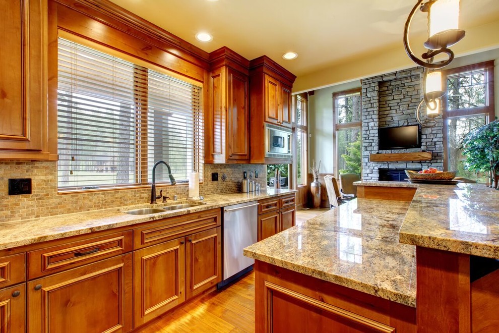 Inspiration for a large transitional l-shaped medium tone wood floor eat-in kitchen remodel in Denver with a double-bowl sink, beaded inset cabinets, medium tone wood cabinets, granite countertops, beige backsplash, matchstick tile backsplash, stainless steel appliances and an island