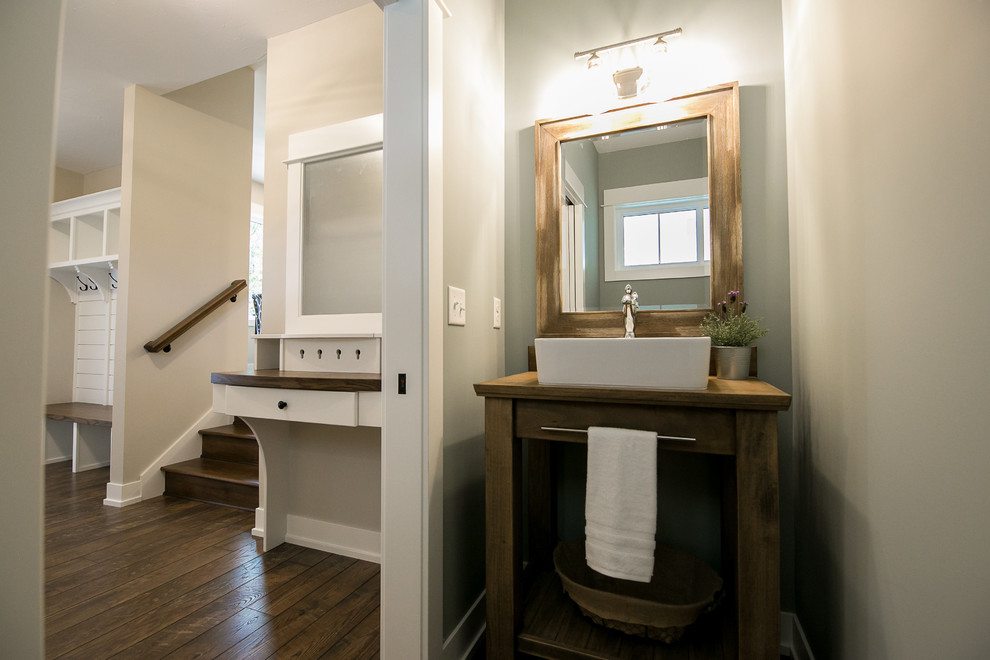 Design ideas for a small country powder room in Grand Rapids with open cabinets, distressed cabinets, a two-piece toilet, laminate floors, a vessel sink, wood benchtops, brown floor and grey walls.