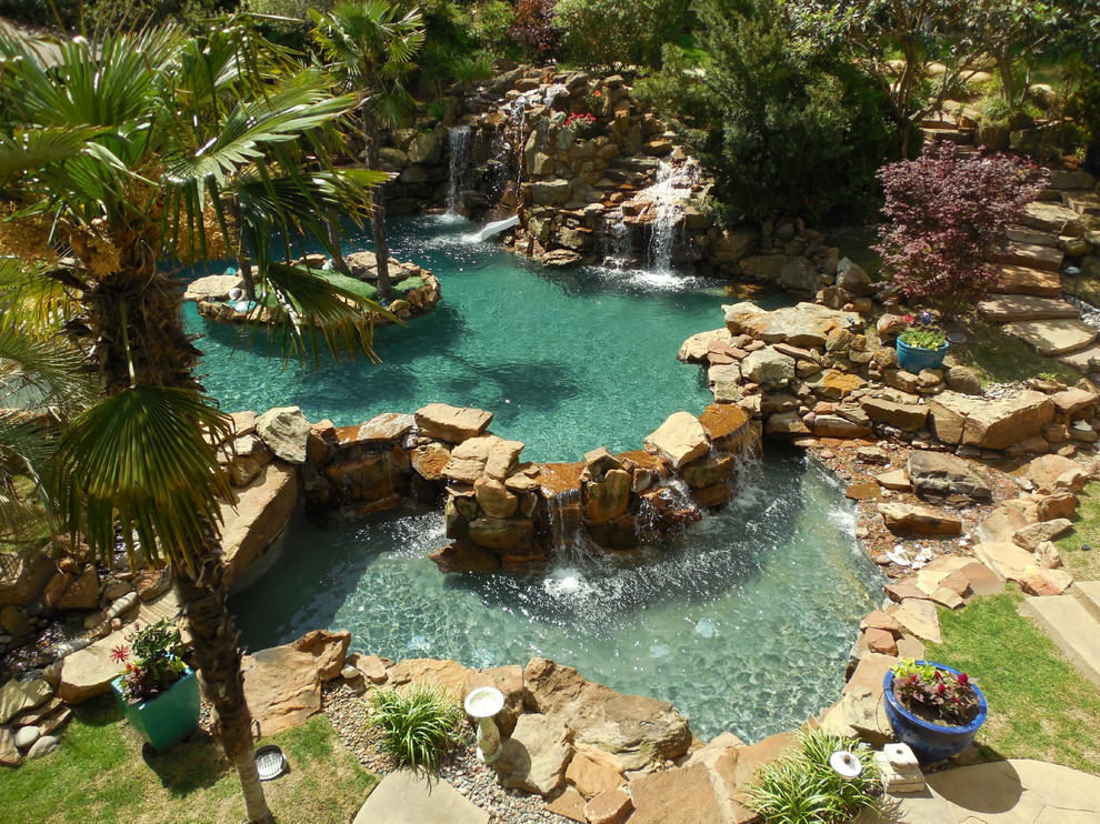 Expansive tropical backyard custom-shaped natural pool in Dallas with a water feature and stamped concrete.