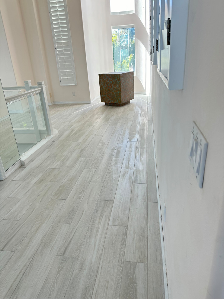 This is an example of a large beach style hallway in Tampa with white walls, porcelain floors, grey floor, vaulted and wallpaper.