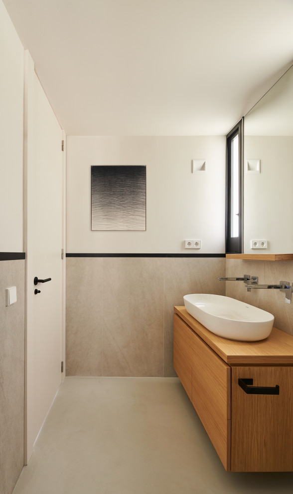 Photo of a large master bathroom in Barcelona with furniture-like cabinets, beige cabinets, a freestanding tub, a curbless shower, a wall-mount toilet, beige tile, ceramic tile, beige walls, concrete floors, a vessel sink, wood benchtops, grey floor, a sliding shower screen, beige benchtops, an enclosed toilet, a single vanity and a built-in vanity.