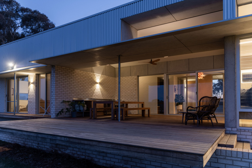 This is an example of a mid-sized contemporary verandah in Other with with columns, decking and a roof extension.