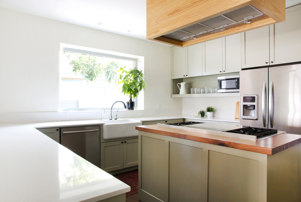 Open concept kitchen - transitional u-shaped dark wood floor open concept kitchen idea in Austin with a farmhouse sink, shaker cabinets, green cabinets, wood countertops, white backsplash, stone slab backsplash, stainless steel appliances, white walls and an island