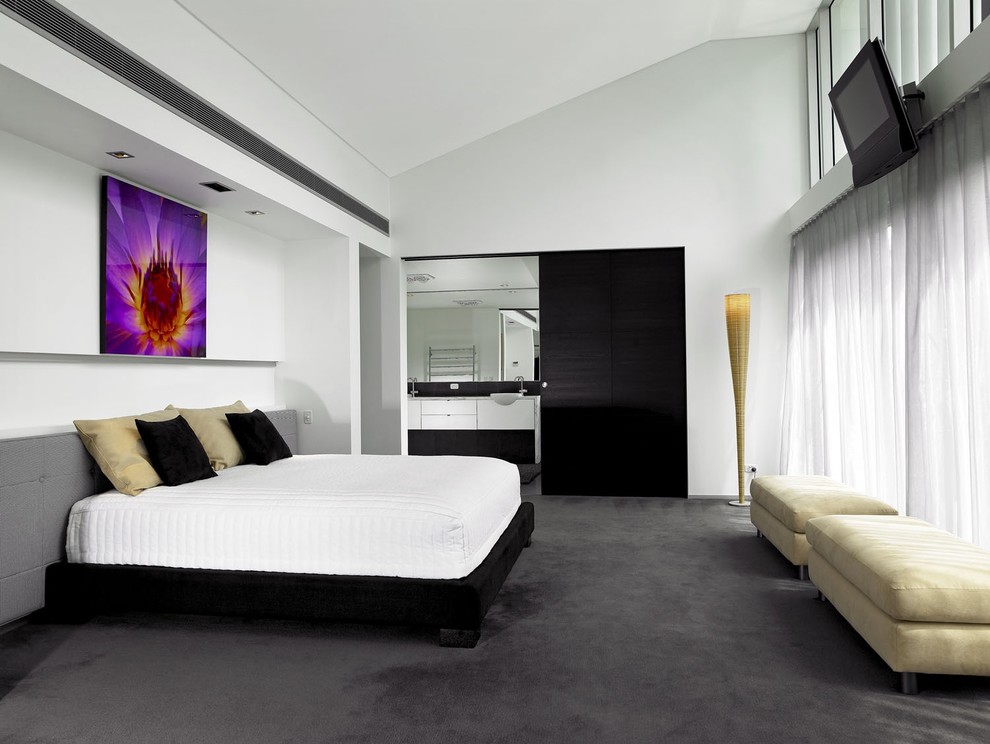This is an example of a contemporary bedroom in Brisbane with white walls and carpet.
