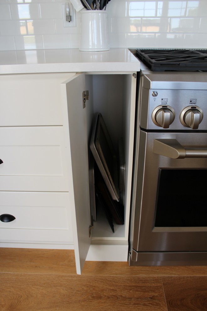 Eat-in kitchen - large transitional l-shaped eat-in kitchen idea in Toronto with an undermount sink, shaker cabinets, white cabinets, quartz countertops, white backsplash, stainless steel appliances and an island