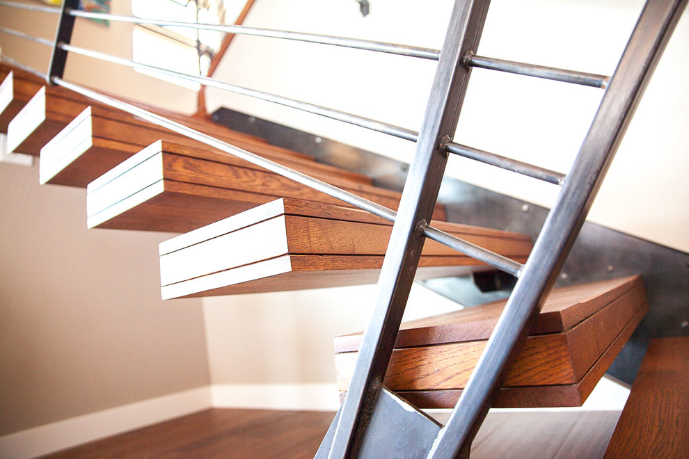 Photo of a large modern wood floating staircase in Denver with open risers and metal railing.