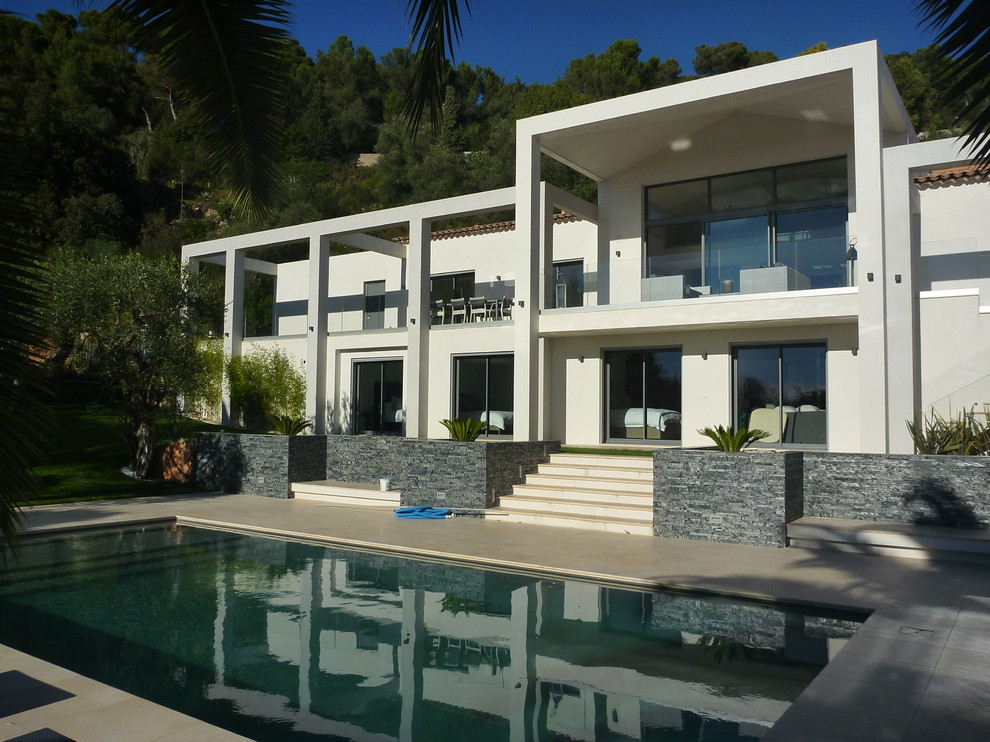 This is an example of a large contemporary two-storey white exterior in Nice with a flat roof.
