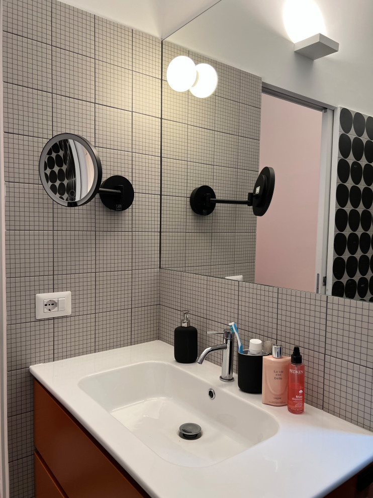 Foto på ett mellanstort funkis vit en-suite badrum, med orange skåp, en toalettstol med separat cisternkåpa, svart och vit kakel, porslinskakel, vita väggar, klinkergolv i porslin, ett integrerad handfat och svart golv