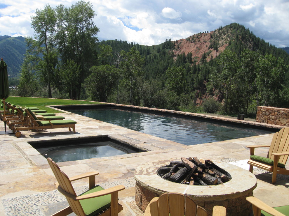Photo of a large country backyard custom-shaped pool in Denver with natural stone pavers.