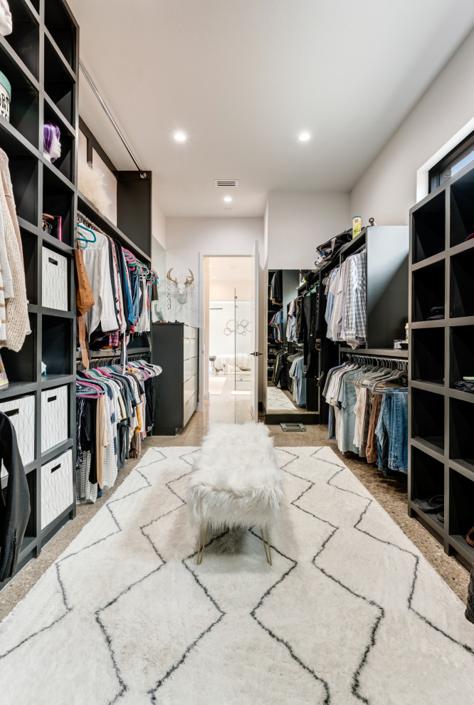 Imagen de armario y vestidor unisex contemporáneo grande con a medida, armarios abiertos, puertas de armario negras, suelo de cemento y suelo gris