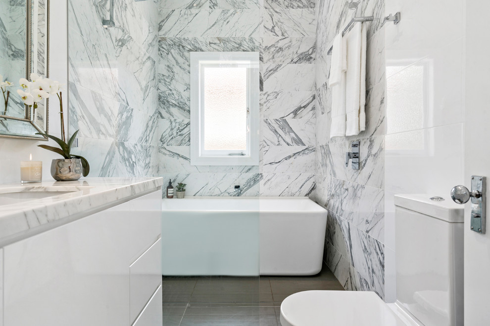 Mid-sized contemporary master wet room bathroom in Sydney with flat-panel cabinets, white cabinets, an undermount tub, a one-piece toilet, white tile, marble, travertine floors, a drop-in sink, marble benchtops, grey floor and a hinged shower door.