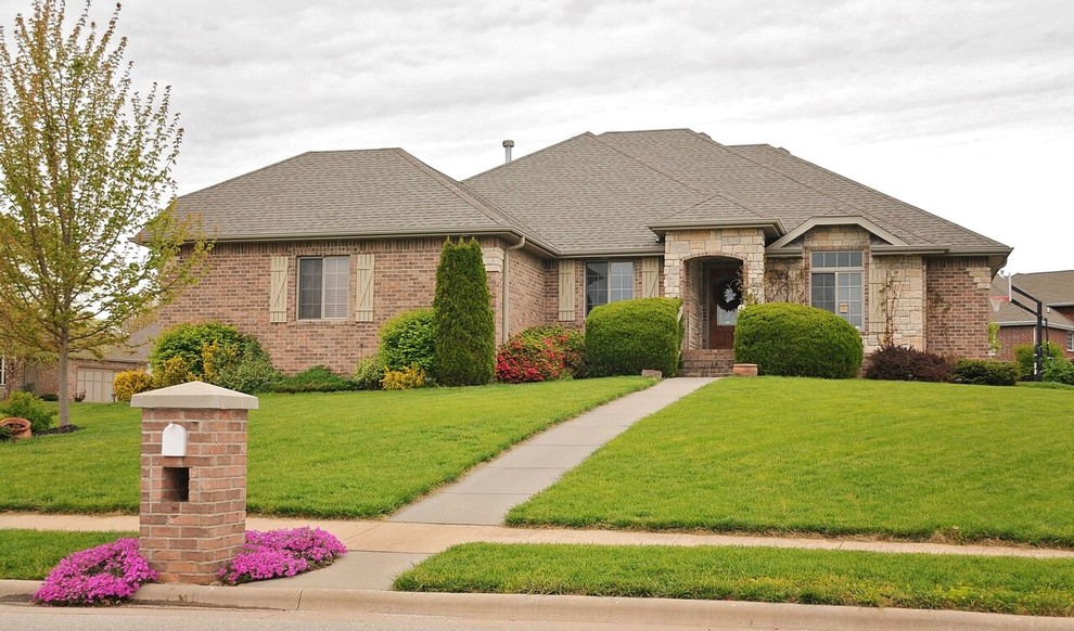 Large transitional brown two-story brick house exterior idea with a hip roof and a shingle roof