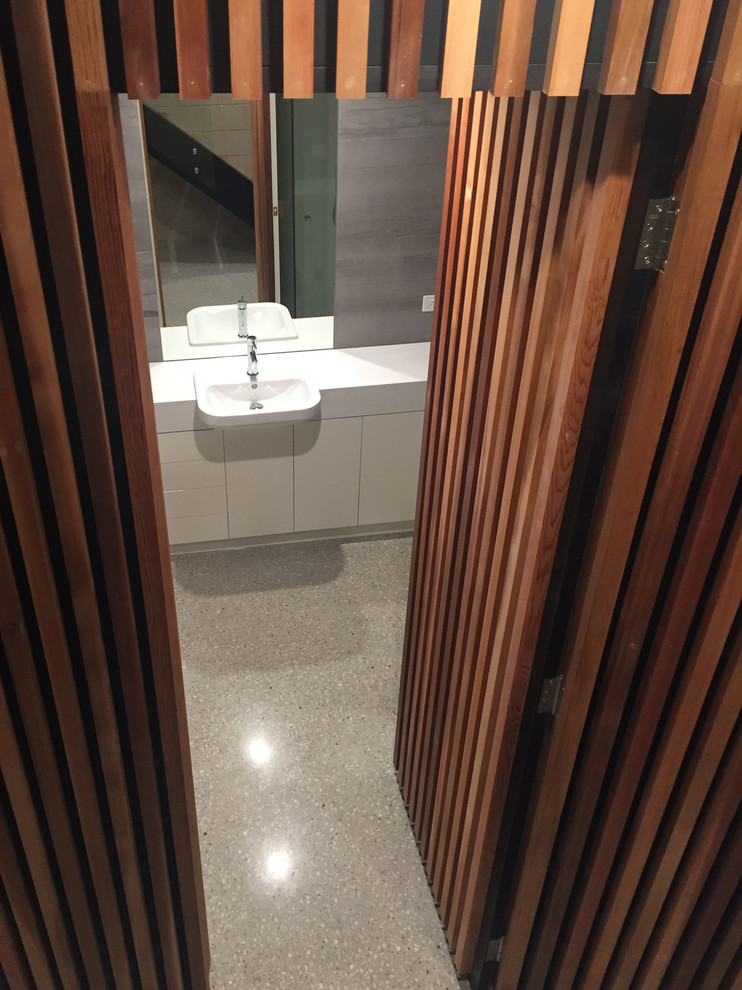 Photo of a mid-sized contemporary kids bathroom in Other with flat-panel cabinets, white cabinets, gray tile, ceramic tile, concrete floors, a drop-in sink, engineered quartz benchtops and beige floor.