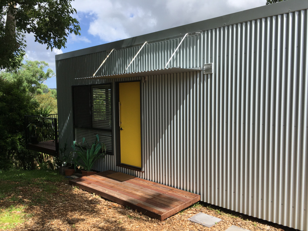 Kleines, Einstöckiges Maritimes Einfamilienhaus mit Metallfassade, grauer Fassadenfarbe, Flachdach, Blechdach und weißem Dach in Sunshine Coast