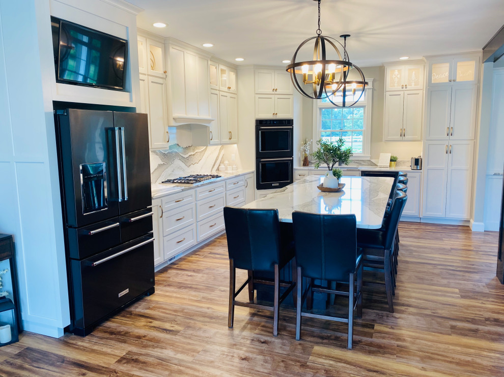 Open concept kitchen - large transitional l-shaped medium tone wood floor and brown floor open concept kitchen idea with an undermount sink, flat-panel cabinets, white cabinets, quartz countertops, multicolored backsplash, quartz backsplash, black appliances, an island and multicolored countertops