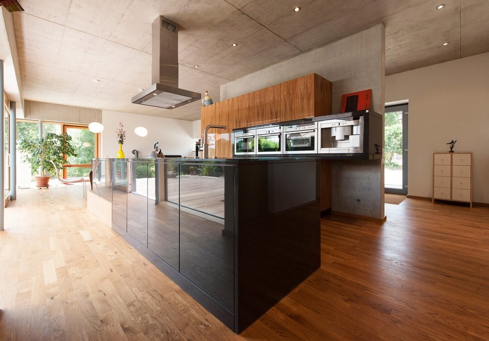 Design ideas for an expansive contemporary open plan kitchen in Stuttgart with flat-panel cabinets, medium wood cabinets, stainless steel appliances, medium hardwood floors and with island.