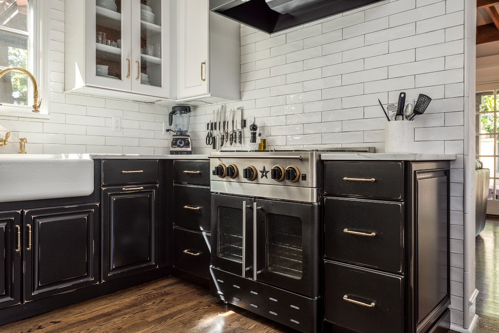 Inspiration for a mid-sized country u-shaped separate kitchen in Tampa with a farmhouse sink, raised-panel cabinets, black cabinets, marble benchtops, white splashback, subway tile splashback, stainless steel appliances, medium hardwood floors, no island, brown floor and white benchtop.