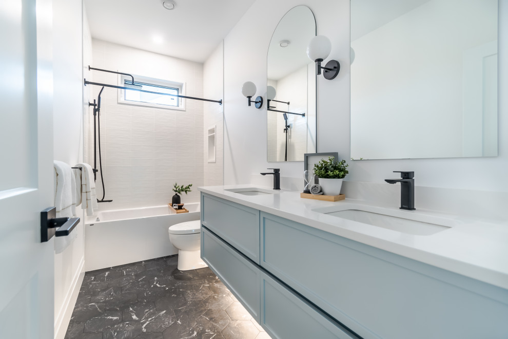 Photo of a large scandi family bathroom in Vancouver with shaker cabinets, blue cabinets, an alcove bath, a shower/bath combination, a one-piece toilet, white tiles, metro tiles, white walls, porcelain flooring, a submerged sink, engineered stone worktops, black floors, a shower curtain, white worktops, a wall niche, double sinks and a floating vanity unit.