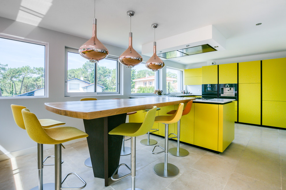 Design ideas for a contemporary kitchen in Other with flat-panel cabinets, yellow cabinets, multiple islands and beige floor.