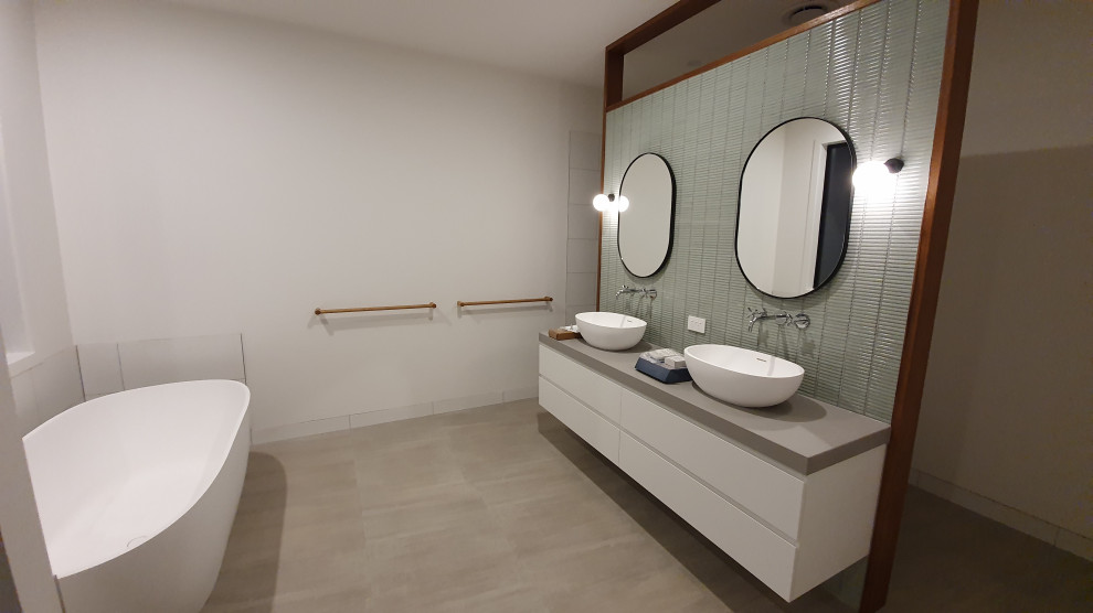 This is an example of a large contemporary master bathroom in Geelong with white cabinets, an alcove shower, a one-piece toilet, green tile, glass tile, white walls, ceramic floors, concrete benchtops, an open shower, grey benchtops, a double vanity and a floating vanity.