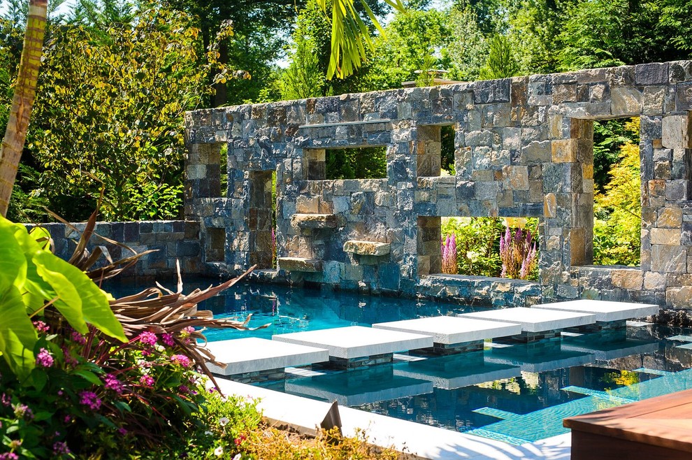 Example of a large backyard stone and custom-shaped pool design in New York