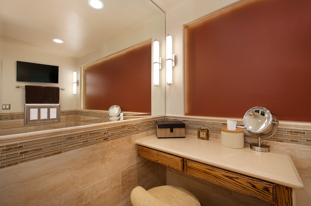 This is an example of a large traditional master bathroom in Orange County with raised-panel cabinets, dark wood cabinets, an undermount tub, a curbless shower, a one-piece toilet, beige tile, glass tile, beige walls, travertine floors, an undermount sink and engineered quartz benchtops.