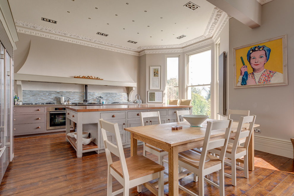This is an example of a large transitional eat-in kitchen in Devon with a double-bowl sink, distressed cabinets, wood benchtops, grey splashback, ceramic splashback, stainless steel appliances, medium hardwood floors and with island.