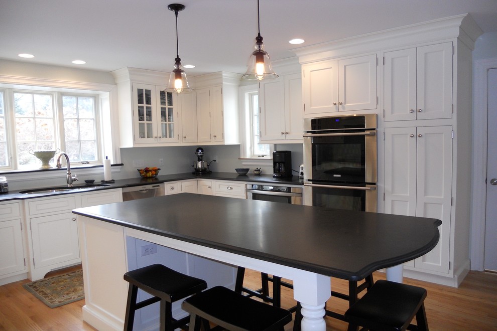 Example of a mid-sized transitional l-shaped light wood floor eat-in kitchen design in Boston with a double-bowl sink, beaded inset cabinets, white cabinets, granite countertops, stainless steel appliances and an island