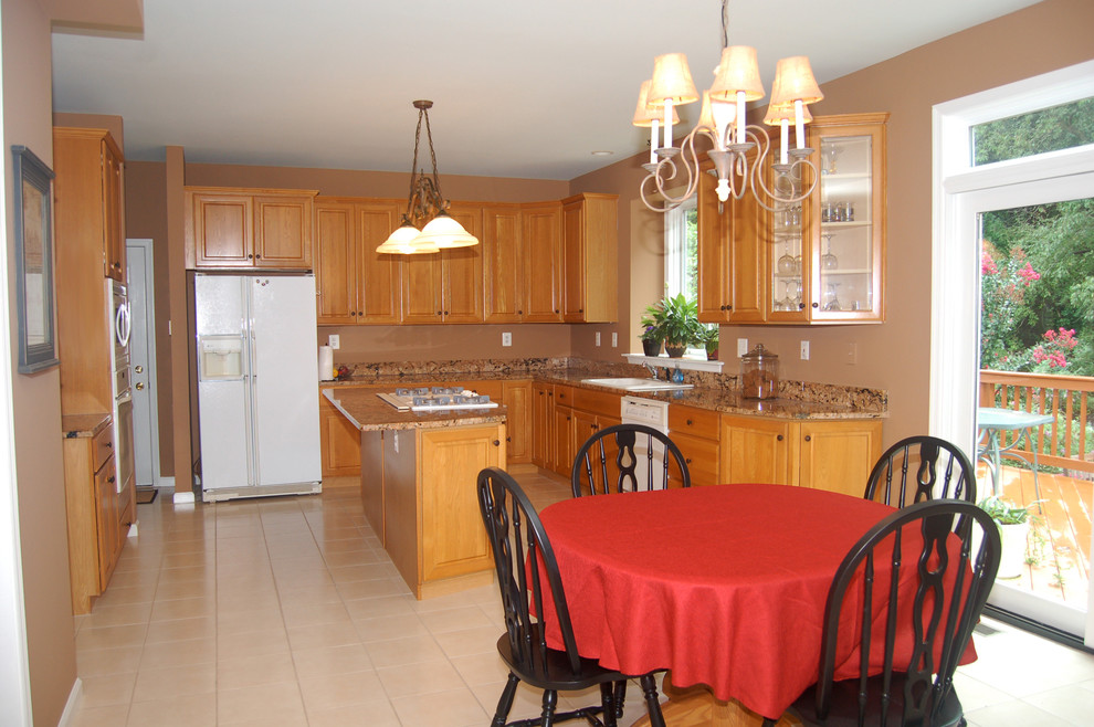 Mid-sized traditional l-shaped eat-in kitchen in Philadelphia with a drop-in sink, raised-panel cabinets, light wood cabinets, granite benchtops, white appliances, ceramic floors and with island.