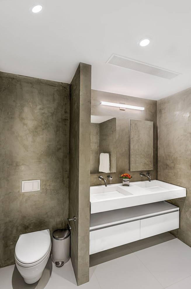This is an example of a large contemporary master bathroom in New York with flat-panel cabinets, white cabinets, a freestanding tub, a corner shower, a wall-mount toilet, gray tile, cement tiles, an undermount sink, engineered quartz benchtops, a sliding shower screen and white benchtops.