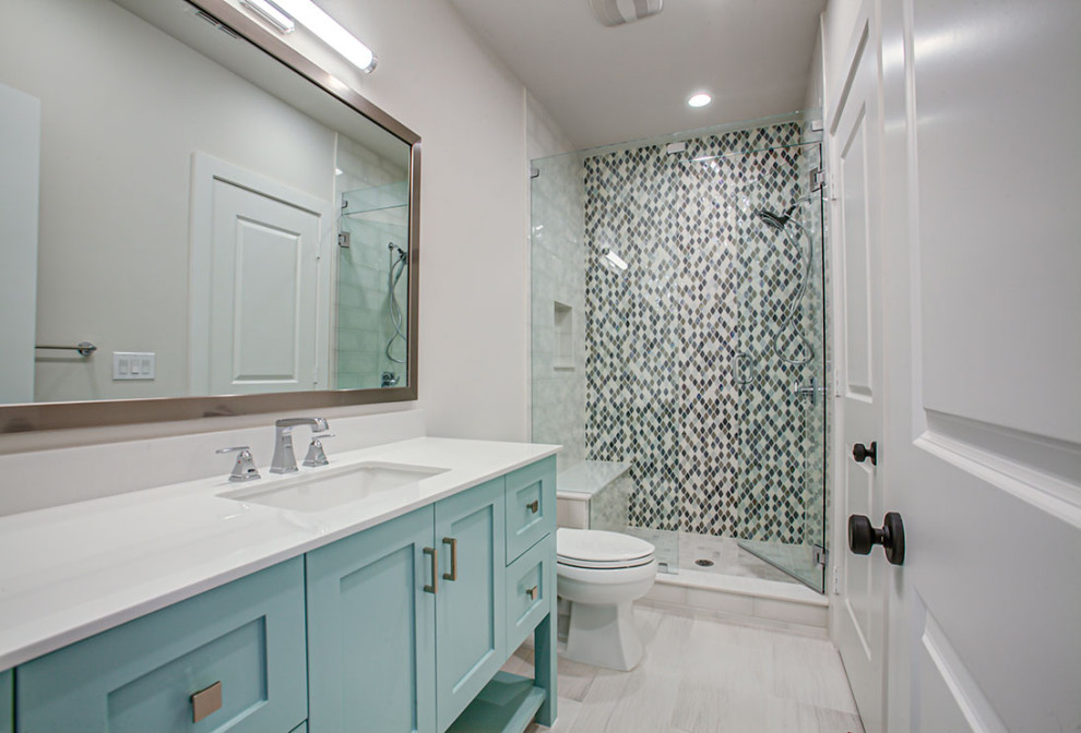 Photo of a large arts and crafts 3/4 bathroom in Dallas with shaker cabinets, blue cabinets, an alcove shower, a one-piece toilet, a hinged shower door, white benchtops, a shower seat, a single vanity and a built-in vanity.