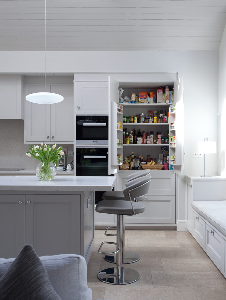 This is an example of a mid-sized transitional galley open plan kitchen in Dublin with recessed-panel cabinets, grey cabinets, black appliances and with island.