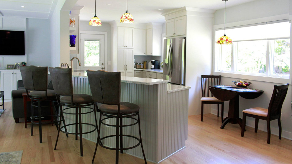 Mid-sized eclectic l-shaped eat-in kitchen in Bridgeport with a double-bowl sink, shaker cabinets, white cabinets, quartz benchtops, green splashback, porcelain splashback, stainless steel appliances, light hardwood floors, a peninsula, brown floor, beige benchtop and coffered.