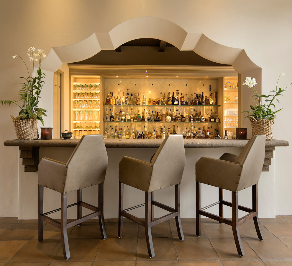 Mediterranean seated home bar in Santa Barbara with beige splashback, ceramic splashback, terra-cotta floors and open cabinets.