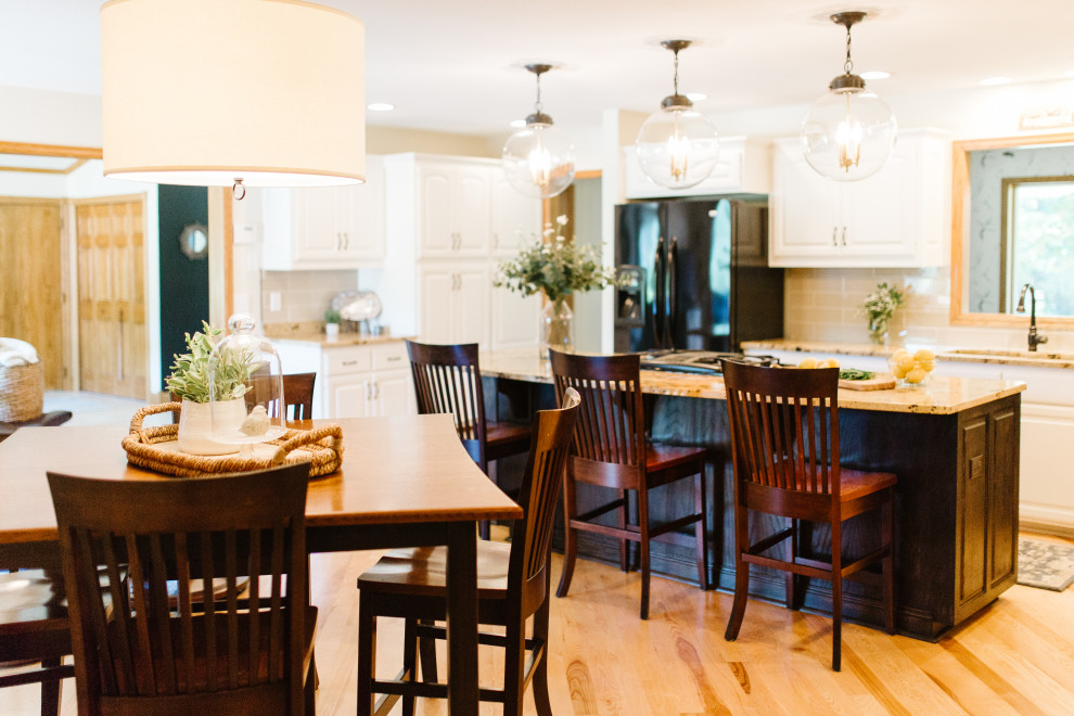 Large transitional u-shaped medium tone wood floor enclosed kitchen photo in Minneapolis with raised-panel cabinets, white cabinets, granite countertops, beige backsplash, subway tile backsplash, black appliances, an island and multicolored countertops