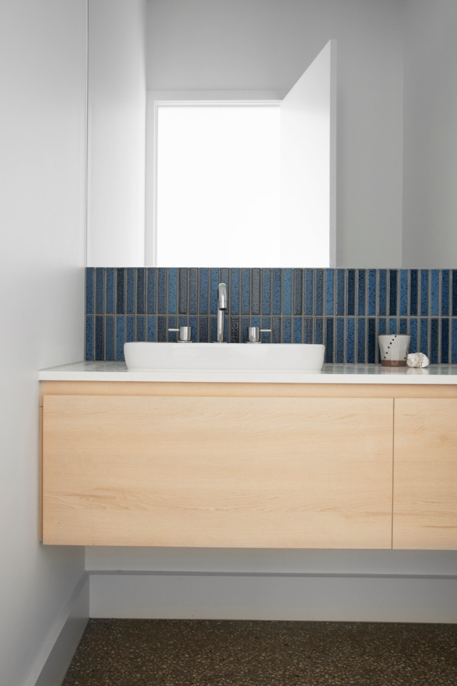 Mid-sized beach style bathroom in Melbourne with flat-panel cabinets, light wood cabinets, a two-piece toilet, blue tile, ceramic tile, white walls, concrete floors, a drop-in sink, engineered quartz benchtops, grey floor, white benchtops, an enclosed toilet, a single vanity and a floating vanity.