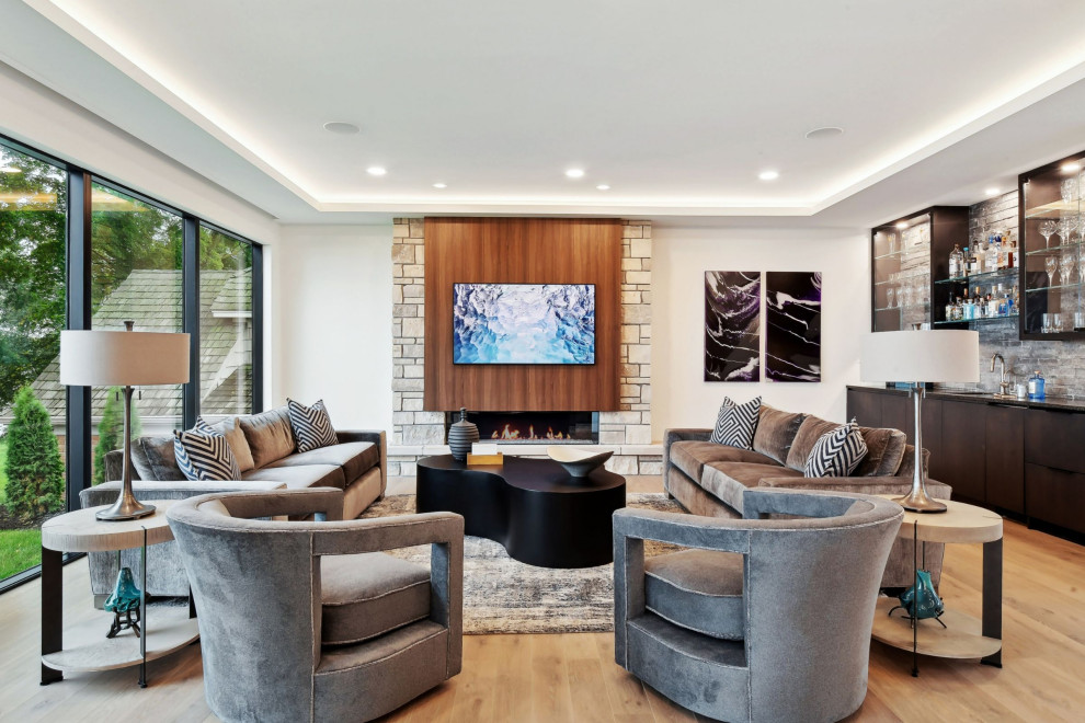 Inspiration for a large contemporary open plan living room in Minneapolis with a home bar, white walls, light hardwood flooring, a standard fireplace, a stacked stone fireplace surround and a wall mounted tv.