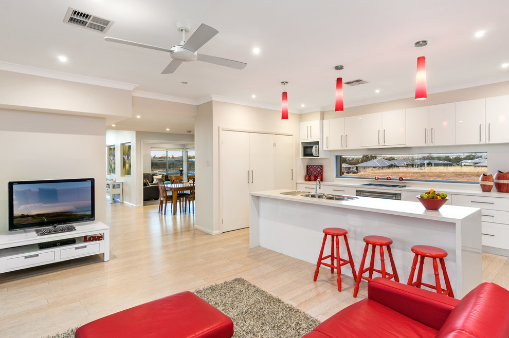 Mid-sized modern galley open plan kitchen in Sydney with a double-bowl sink, white cabinets, quartz benchtops, stainless steel appliances, light hardwood floors and with island.