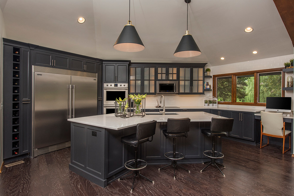 Kitchen - transitional u-shaped dark wood floor kitchen idea with an undermount sink, shaker cabinets, gray cabinets, white backsplash, subway tile backsplash, stainless steel appliances and an island