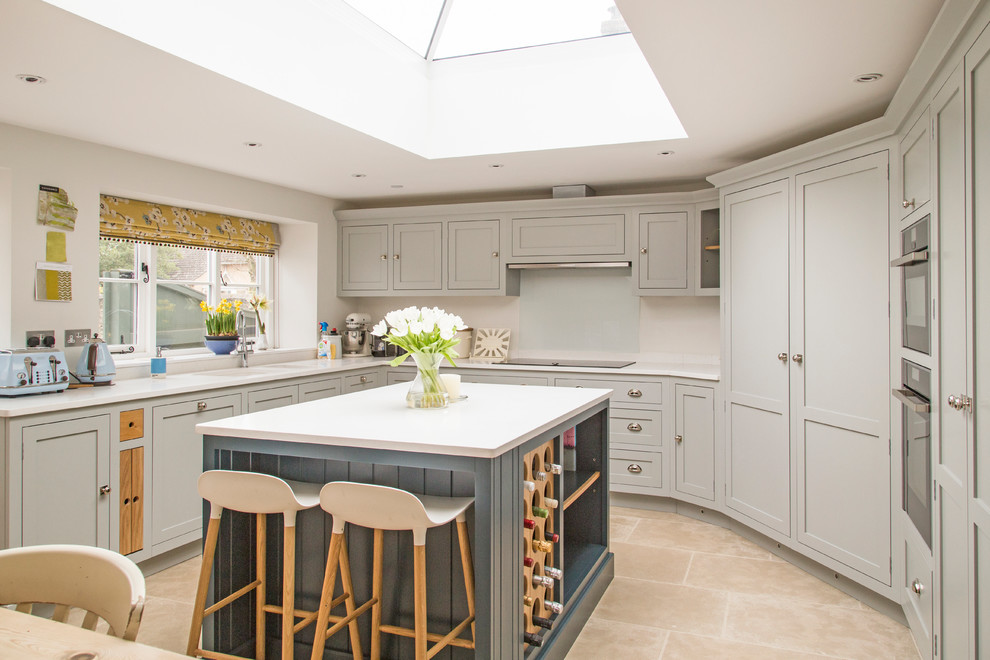 Transitional eat-in kitchen in Gloucestershire with shaker cabinets, grey cabinets, glass sheet splashback and with island.
